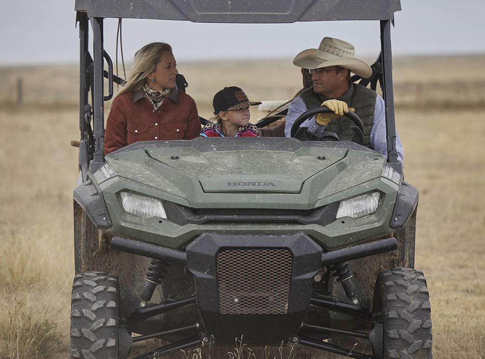 Una familia viajando en un vehículo todo terreno en el pasto mirando a su alrededor.